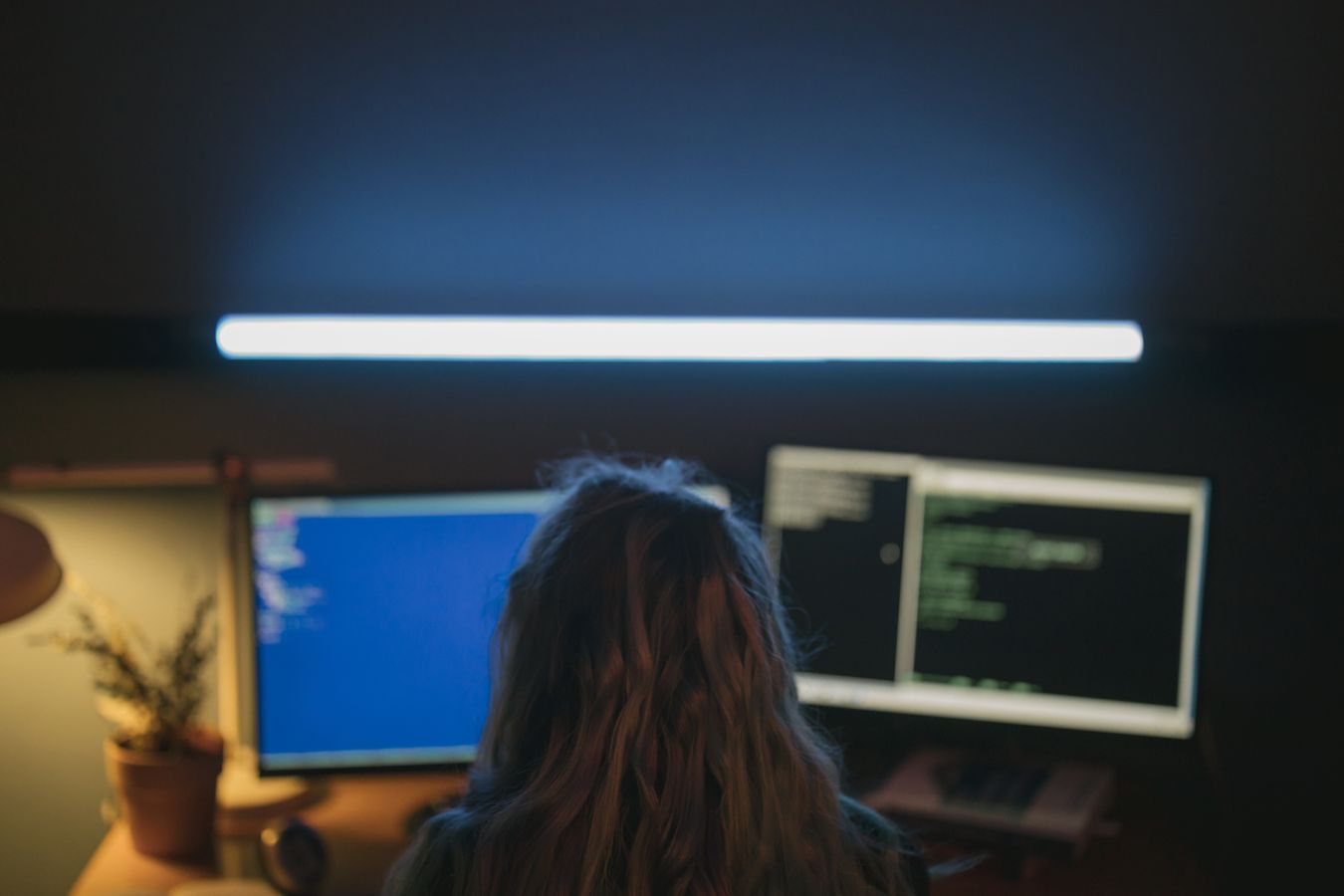An engineer working at a desk with code visible on two monitors